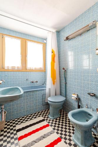 a blue tiled bathroom with a toilet and a sink at Sunny Mountain in Reckingen - Gluringen