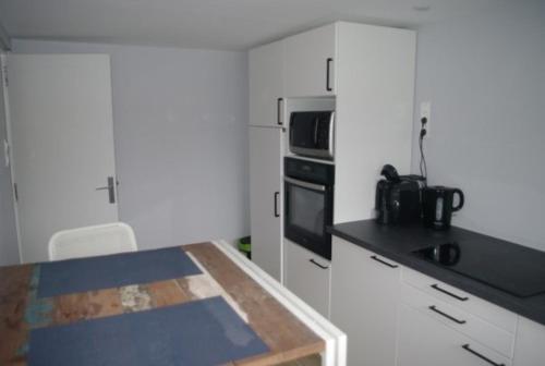 une cuisine avec des armoires blanches et un comptoir noir dans l'établissement Le St Laurent, à Plérin