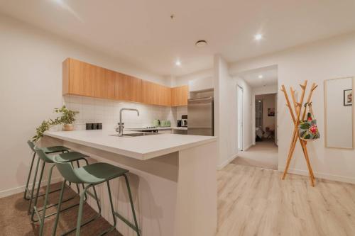 cocina con fregadero y encimera con taburetes en Convenient City Pad - 2BR Laundry Sleeps 5, en Christchurch