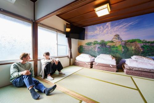 a man and a boy sitting in a room with a mural at SAMURAI Base in Hakone