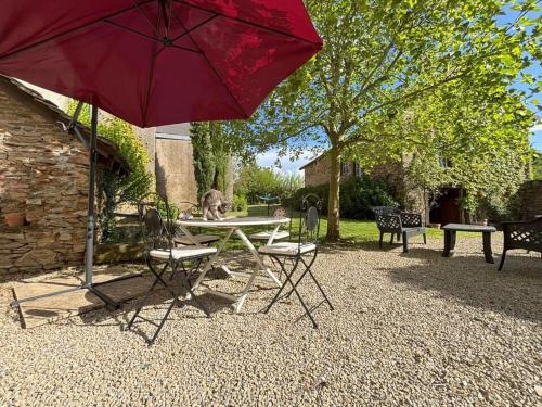 a picnic table and chairs with a red umbrella at Aux 12 instants, Imagine in Lédergues