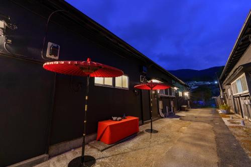 two red umbrellas and a red table on a street at SAMURAI Base in Hakone
