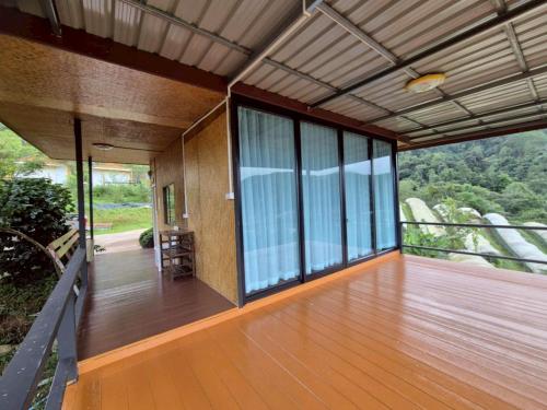a house with a balcony with a view of the forest at Doymoktawanview ดอยหมอกตะวันวิว in Ban Yang Di Pha Mop