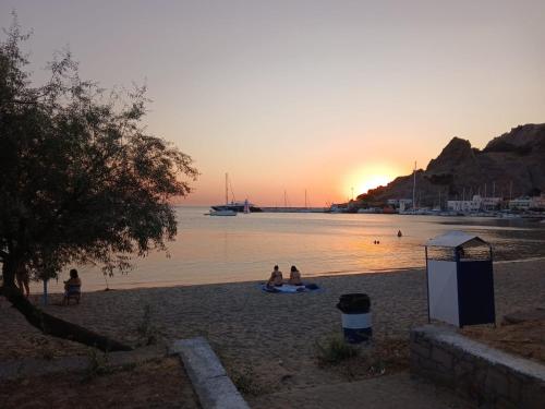 a group of people sitting on the beach at sunset at Charming Town House, Limani 9 in Mirina