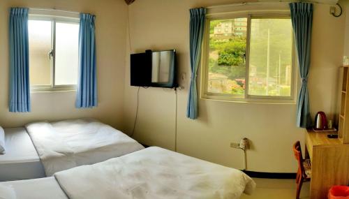 a room with two beds and a tv and a window at 津沙小筑 in Nangan