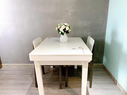 a white table with a vase of flowers on it at The Sun Avenue Serviced Apartment in Ho Chi Minh City