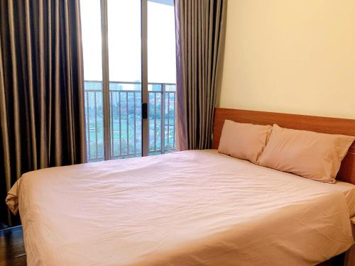 a bed in a room with a large window at The Sun Avenue Serviced Apartment in Ho Chi Minh City
