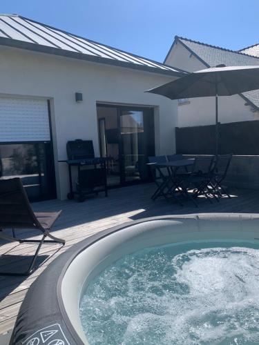 a swimming pool with a table and chairs and an umbrella at LE REFUGE DE LA BAIE in Beaussais sur Mer