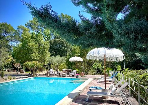 une piscine avec des chaises longues et un parasol dans l'établissement Cottages at Les Pervenches, à Lorgues