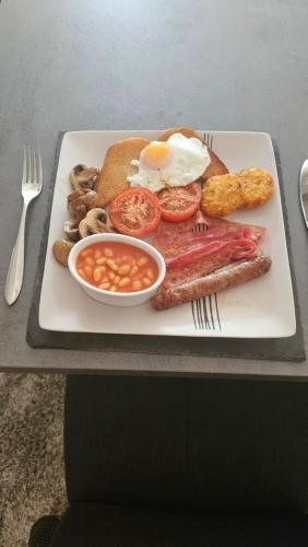 a plate of breakfast food with eggs bacon beans and toast at The Lions Den - La Loge Guest House in Mantilly