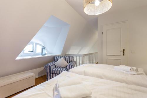 a attic bedroom with two beds and a chair at Landhaus Butt 05 in Ahrenshoop