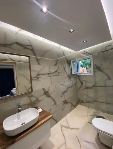 a bathroom with a sink and a toilet and a mirror at Relax Apartments SB in Himare