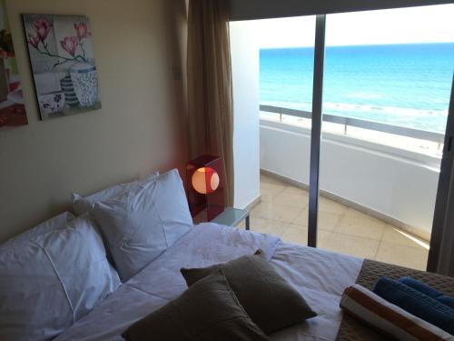 Un dormitorio con una cama con vista al mar. en Alex Beach Apartment 51, en Lárnaca