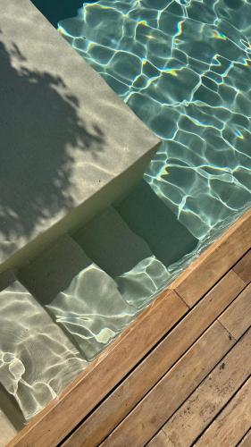 a pool with a wooden deck and water in it at Casa de Afora Casa con piscina y jacuzzi privados in Santiago de Compostela