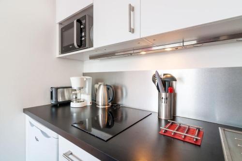 une cuisine avec un comptoir noir avec un micro-ondes dans l'établissement Studio lumineux Lyon, à Lyon
