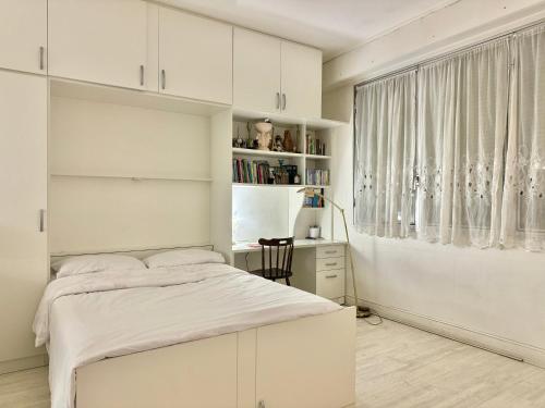 une chambre blanche avec un lit et un bureau dans l'établissement Small Cosy Studio in Paris, à Paris