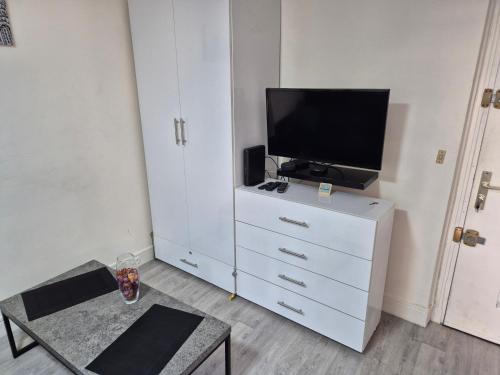 - un salon avec une commode blanche et une télévision dans l'établissement Studio très calme, à Paris