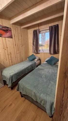 two beds in a cabin with a window at Domki Rekreacyjne "Błękitne Wzgórze" in Żałe