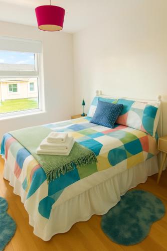 a colorful bed in a room with a window at The South Promenade apartment in Newcastle