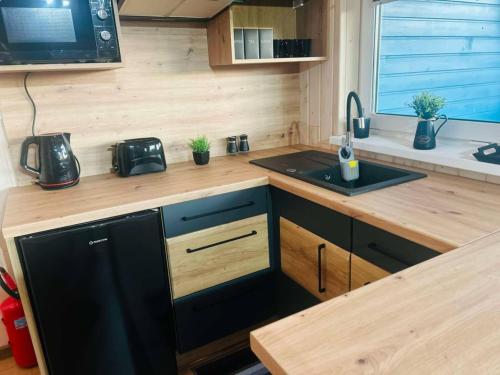 a kitchen with a black refrigerator and a sink at Domki Rekreacyjne "Błękitne Wzgórze" in Żałe