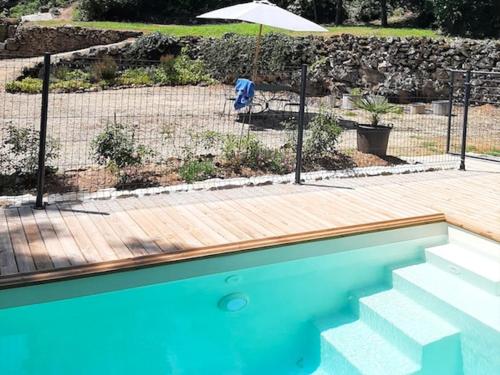 une maison avec une piscine et un parasol dans l'établissement Gîte de vacances La Melve, à Milhac