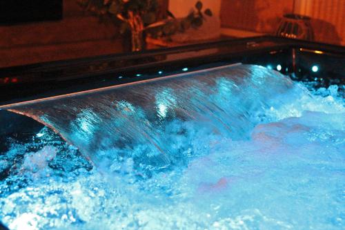 un bain à remous rempli d'eau bleue avec une cascade dans l'établissement Love Room La Crèche Romantique, à Bogny Sur Meuse