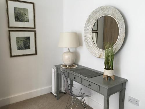 a table with a lamp and a mirror on it at The Bungalow and Studio Apartments in Lytham St Annes