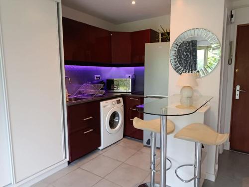 une cuisine avec un lave-linge et une table en verre dans l'établissement Studio - L'Ancre Grise, à La Rochelle