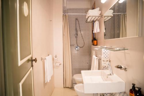 a white bathroom with a sink and a toilet at Hotel Carasco in Lipari