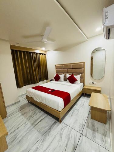 a bedroom with a large bed with red pillows at Hotel BK Palace AC Rooms in Vadodara