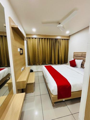 a bedroom with a large bed with a red blanket at Hotel BK Palace AC Rooms in Vadodara