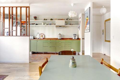 une cuisine avec une table et des armoires vertes dans l'établissement Magnifique Appartement avec vue sur Tour Eiffel avec 3 chambres, à Paris