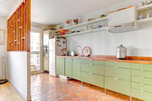 - une cuisine avec des placards verts et un réfrigérateur dans l'établissement Magnifique Appartement avec vue sur Tour Eiffel avec 3 chambres, à Paris