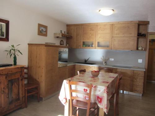 una cocina con armarios de madera y una mesa con mantel. en Les Racines en Rhêmes-Notre-Dame