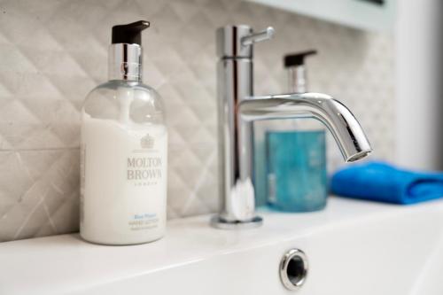a bottle of soap sitting on a bathroom sink at The Open 2025 Accommodation in Ballycastle