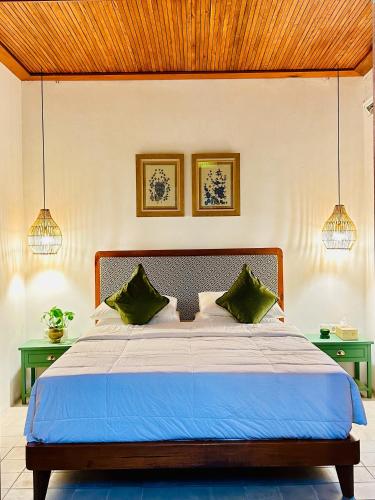 a bedroom with a bed with two green tables at Omah Jago Sentana Yogyakarta in Timuran