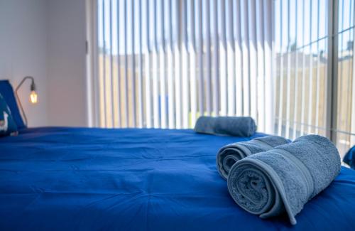 a blue bed with two rolled towels on it at The Open 2025 Accommodation in Ballycastle