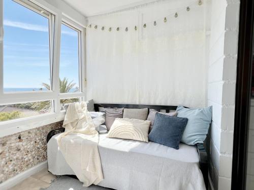 een slaapkamer met een bed met kussens en een raam bij The house of secrets in Torrevieja