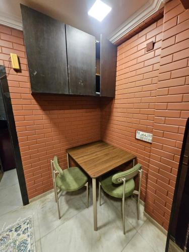 a kitchen with a wooden table and two green chairs at Brick Maison 1BHK with Free Parking, Juhu Bandra in Mumbai