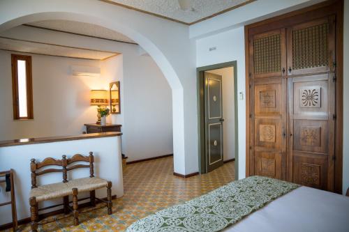 a bedroom with a bed and two chairs and a door at Hotel Carasco in Lipari