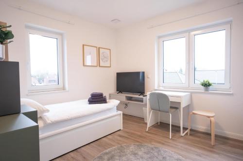 a white room with a bed and a desk and a tv at Wackenhuus 5 Albersdorf in Albersdorf