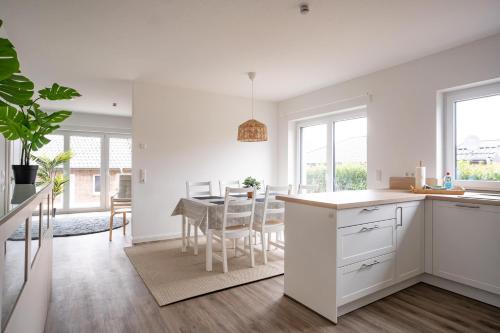 a kitchen and dining room with white cabinets and a table at Wackenhuus 4 Albersdorf in Albersdorf
