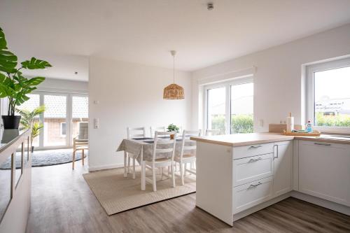 a kitchen and dining room with white cabinets and a table at Wackenhuus 4 Albersdorf in Albersdorf
