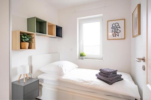 a white bedroom with a bed and a window at Wackenhuus 4 Albersdorf in Albersdorf