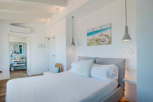 a white bedroom with a large bed with white pillows at Hostal Perla Blanca Altea in Altea