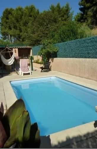 une piscine bleue avec un hamac dans un jardin dans l'établissement Maison au pied du garlaban, à Aubagne