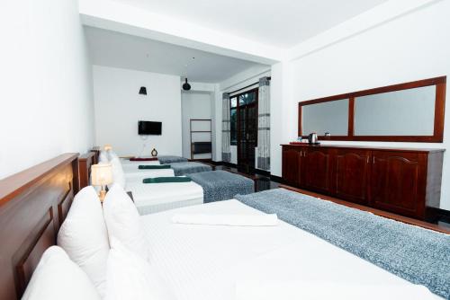 a room with four beds and a flat screen tv at Adams Peak Inn in Adams Peak