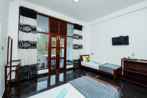 a living room with a couch and a television in a room at Adams Peak Inn in Adams Peak