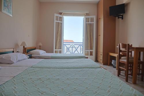 a hotel room with three beds and a large window at Athos Studios in Tinos Town