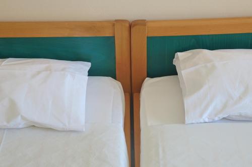 two beds with white pillows sitting next to each other at Athos Studios in Tinos Town